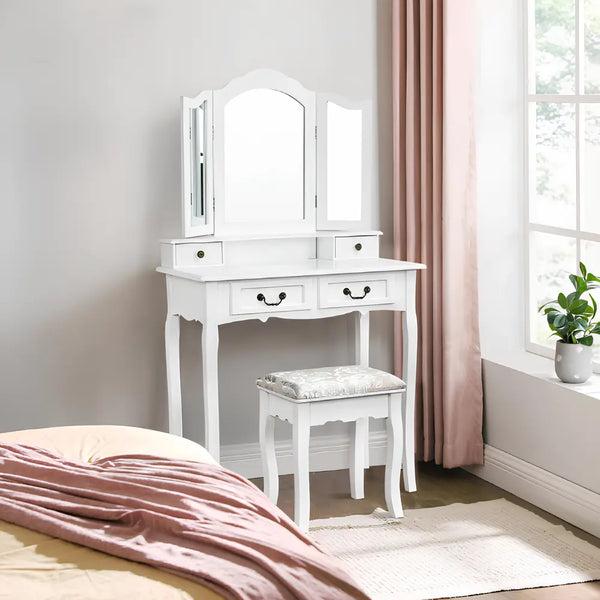 Coiffeuse blanche CELERA avec miroir triptyque et tabouret, éclairée par la lumière naturelle d’une chambre élégante
